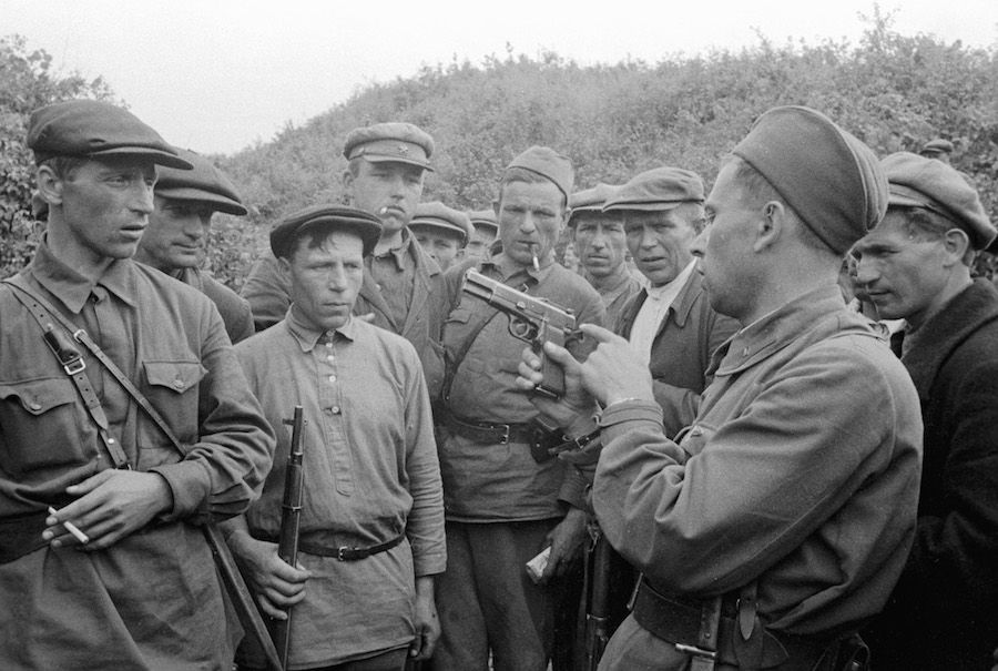 Командир партизанского отряда знакомит бойцов с оружием
